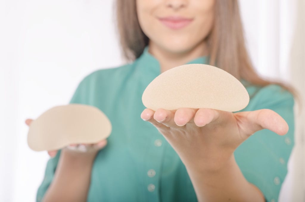 woman holding silicone breast implants